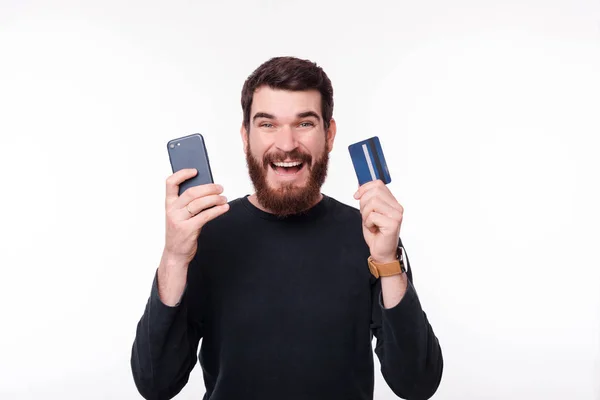 Retrato del hombre feliz sosteniendo teléfono y tarjeta de crédito — Foto de Stock