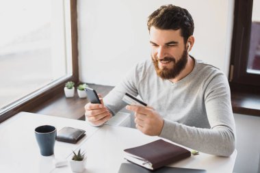 Kredi kartı ve holdin bakarak rahat yakışıklı gülümseyen adam