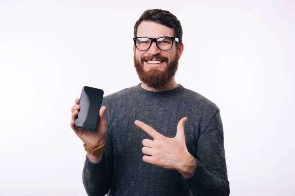 Un homme pointant son téléphone à écran blanc. Il porte des lunettes et un pull gris . — Photo