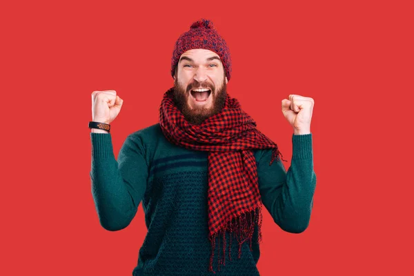 Wesoły i podekscytowany młody człowiek z brodą świętuje sukces na czerwonym tle — Zdjęcie stockowe