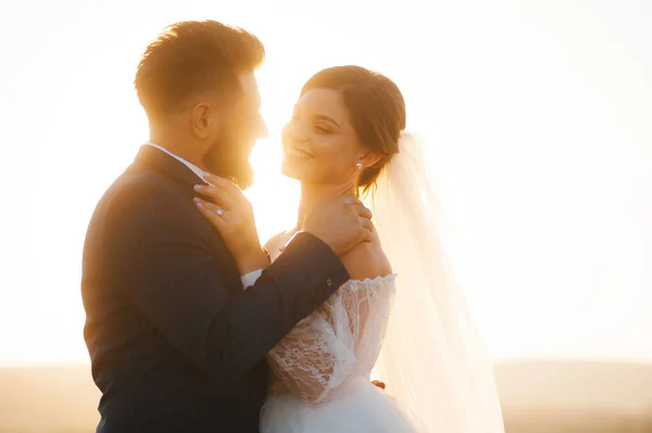 Preciosa pareja vestida con ropa de boda están mirando y sonriendo el uno al otro . — Foto de Stock