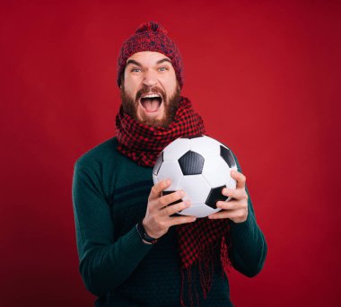 Futbol topu tutan neşeli adam kırmızı arka planda mutluluk çığlıkları atıyor..