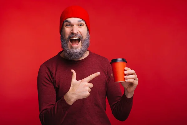 Amazed man with white beard pointing at red cup of coffee