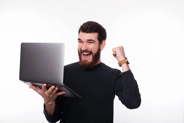 Photo de l'homme souriant célébrer la victoire et tenant ordinateur portable sur fond blanc — Photo
