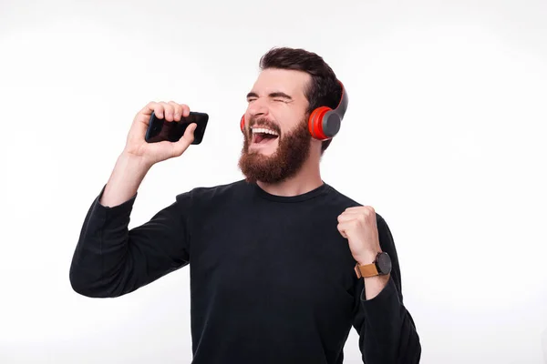 Joven feliz en música casual escuchando en auriculares rojos inalámbricos —  Fotos de Stock
