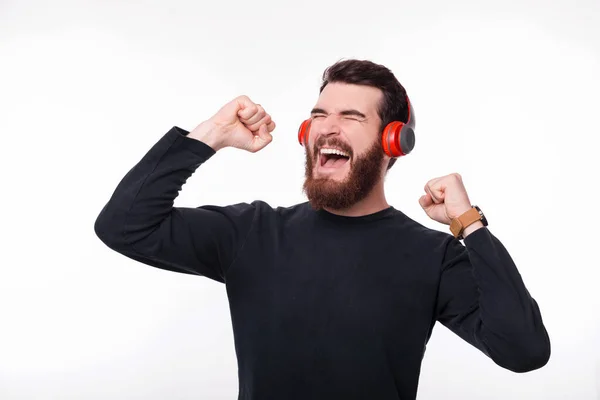 Emocionado joven barbudo escuchando música en auriculares inalámbricos —  Fotos de Stock