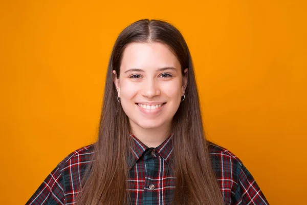 Foto de cerca de la joven sonriente mirando con confianza a la cámara, de pie sobre el fondo amarillo — Foto de Stock