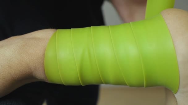 Felvételek az emberről, amint ragasztószalagot vagy fogselymet készít a karján, kineziológia — Stock videók