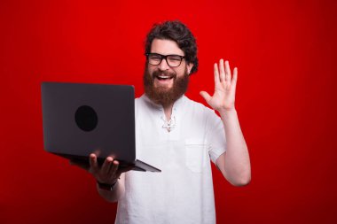 Mutlu adamın bilgisayarda biriyle konuştuğu ve selam verdiği fotoğraf.