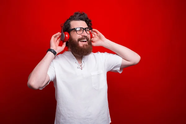 Foto de cara barbudo ouvindo música sobre fundo vermelho — Fotografia de Stock