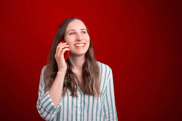 Vidám lány beszél telefonon a piros háttér a stúdióban — Stock Fotó