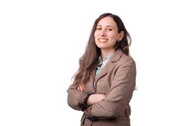 Kameraya gülümseyen genç bir kadın kollarını beyaz arka planda çapraz yapıyor.