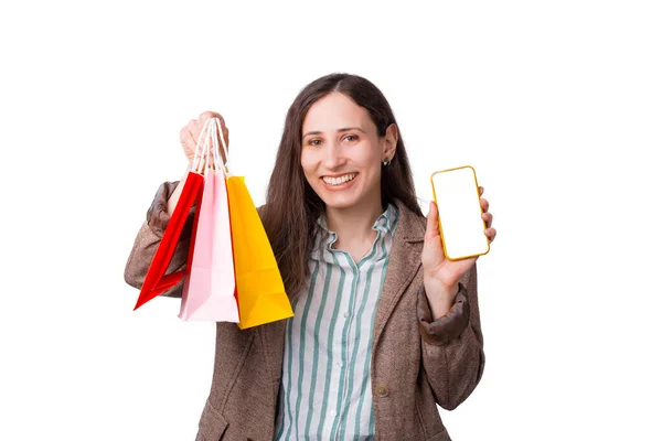 Verspil geen tijd - shop online. Meisje houdt boodschappentassen en telefoon over witte achtergrond — Stockfoto