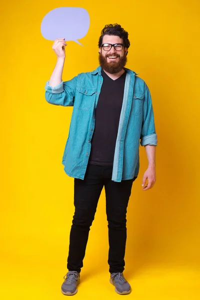 快乐的满脸胡须的男人对着摄像机笑着 站在黄色的背景上发表着紫色的泡泡演讲 — 图库照片