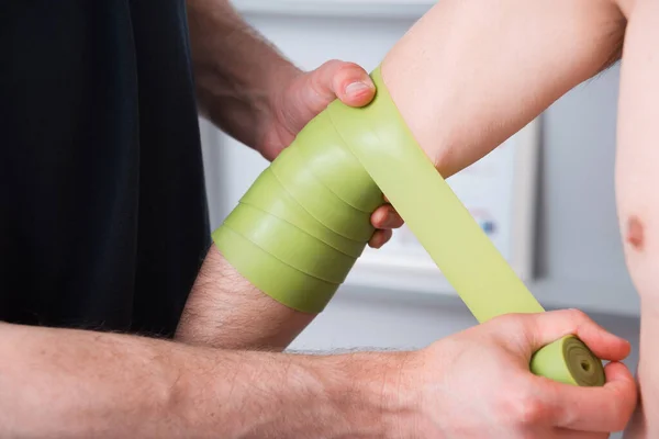 Elbow pain therapy with kinesio green tape.
