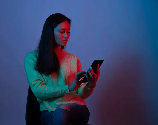 Retrato Uma Jovem Mulher Usando Telefone Fundo Roxo Está Sentado — Fotografia de Stock