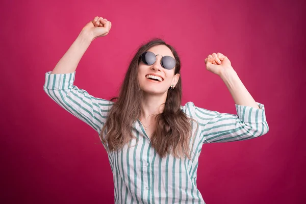 Szczęśliwa Kobieta Okularach Przeciwsłonecznych Robi Gest Zwycięzcy Różowym Tle — Zdjęcie stockowe