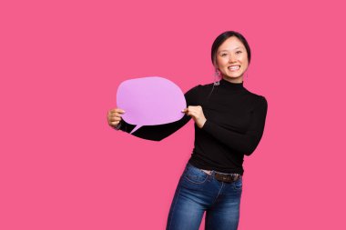 Kameraya gülümseyen neşeli kadın pembe arka planda mor bir balon konuşması yapıyor.