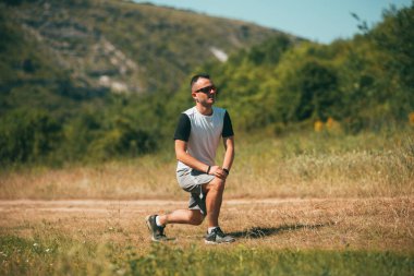 Genç adam tarlada ısınma egzersizleri yapıyor..