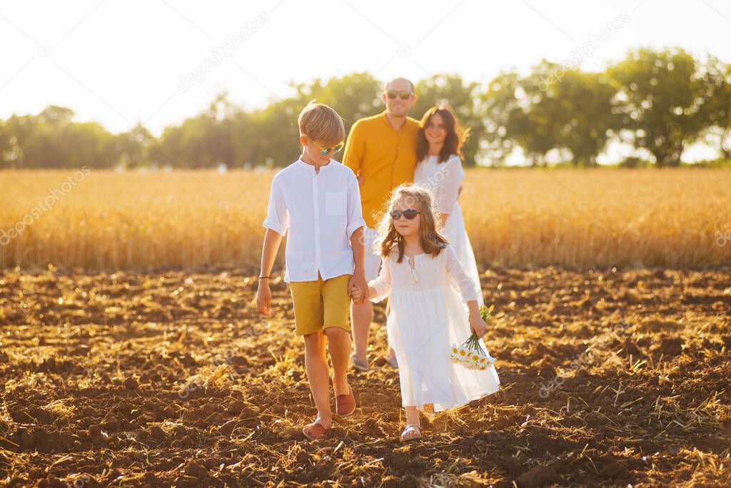 Happy family of four in a field, all dressed in white.