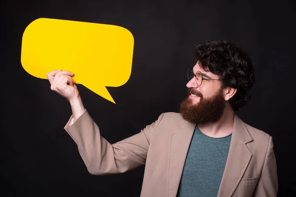 Photo of bearded man in casual looking and holding yellow speech bubble