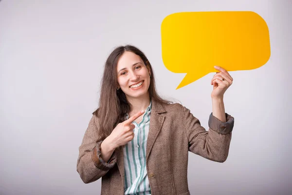 Cheerful smiling young woman is holding a yellow bubble speech over white background — Stock Photo, Image