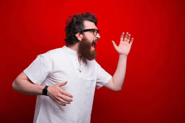 Sietős szakállas férfi weating szemüveg fut át a piros háttér — Stock Fotó