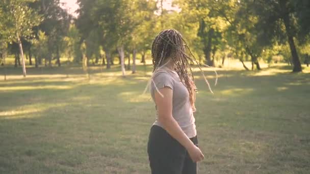 太陽の光の下でボックスブレイドを持つ若い女性の映像 — ストック動画