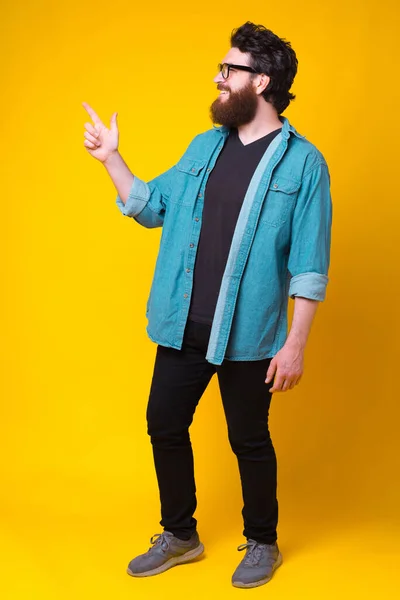 Foto de homem barbudo de comprimento total alegre apontando para longe — Fotografia de Stock