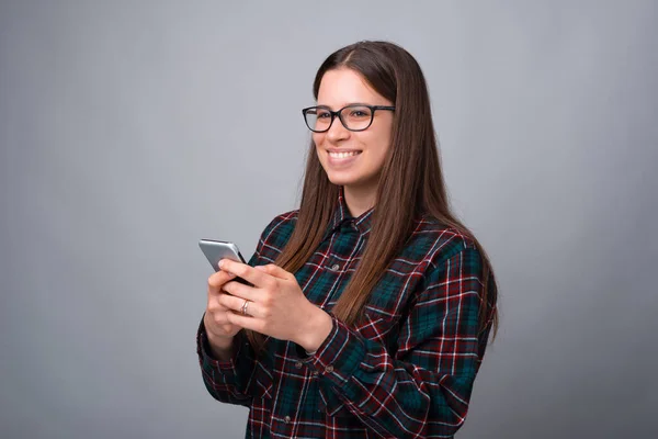 Gyönyörű fiatal nő néz messze, miközben tartja a telefonját — Stock Fotó