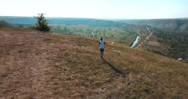 Yaz boyunca tepelerde koşan bir adamın hava aracı görüntüsü.