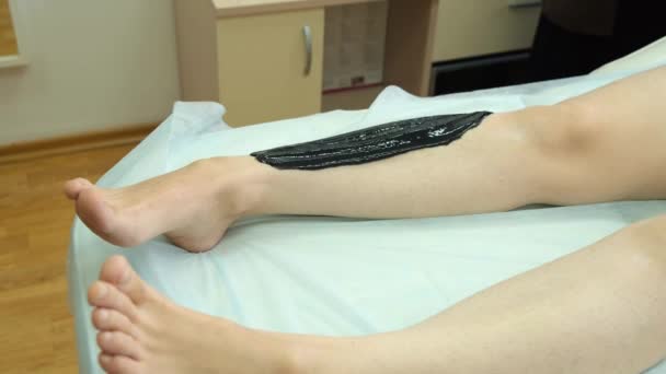 Beelden van een vrouw die suiker maakt op haar been met zwarte pasta — Stockvideo