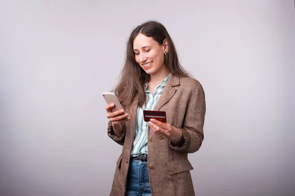 Photo of happy young woman in casual using mobiel phone and holding credit card — Stock Photo, Image