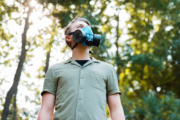 Foto di uomo che indossa respiratore facciale all'aperto nel parco e distogliendo lo sguardo — Foto Stock