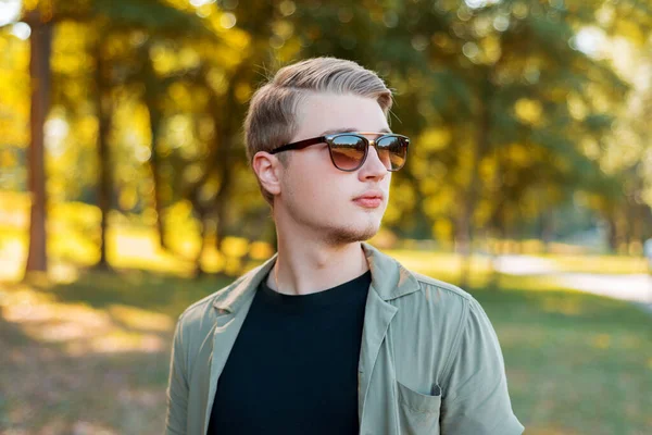 Retrato de homem elegante bonito jovem com óculos de sol standiing ao ar livre — Fotografia de Stock