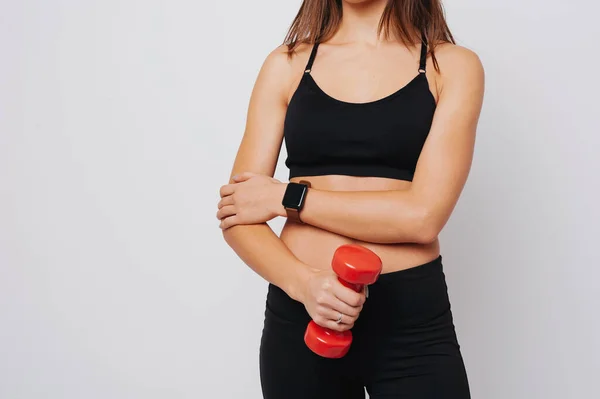 Woman is holding a red dumbbel wearing a fitness watch — Stock Photo, Image