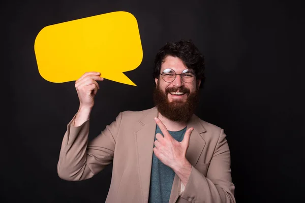 Glücklich lächelnder Mann mit Bart, lässig auf leere Sprechblase zeigend — Stockfoto