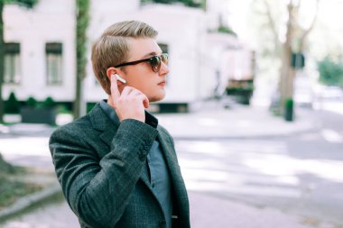 Şehirde kulaklık takan takım elbiseli bir gencin portresini kapat.