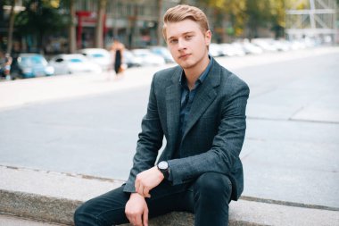 Takım elbiseli genç adamın portresi şehirdeki kameraya kendinden emin bakıyor.