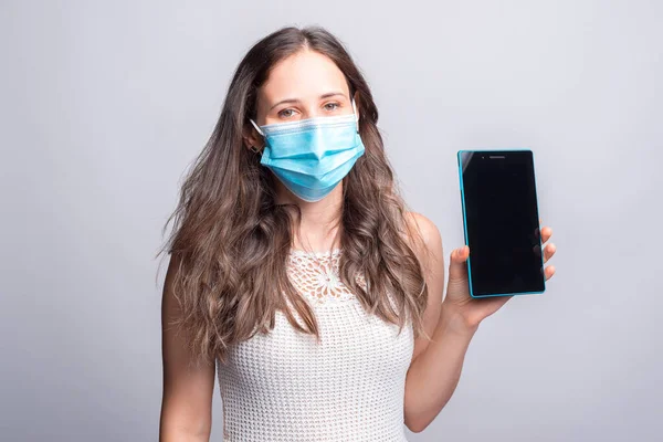 Ritratto di giovane donna che indossa una maschera medicinale che mostra lo schermo del tablet — Foto Stock