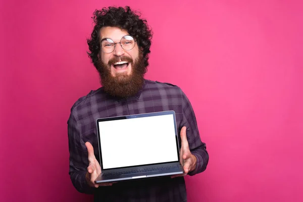 Photo de jeune homme hipster barbu étonné tenant ordinateur portable avec écran blanc vide — Photo