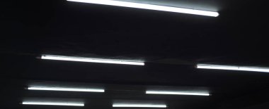 Siyah tavanda uzun lambalar var..