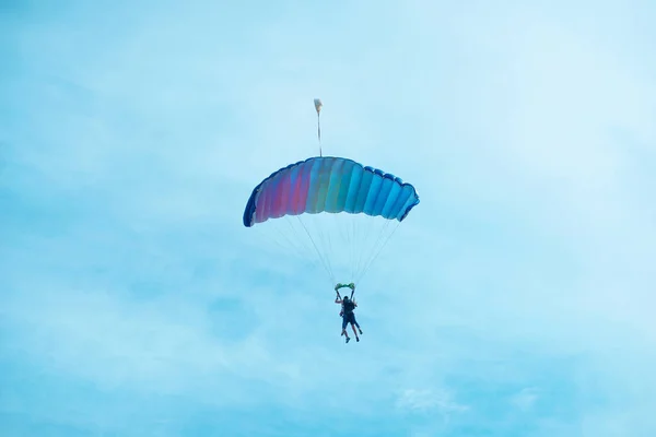 Photo of people jumping with parachute in a beautiful clean day.