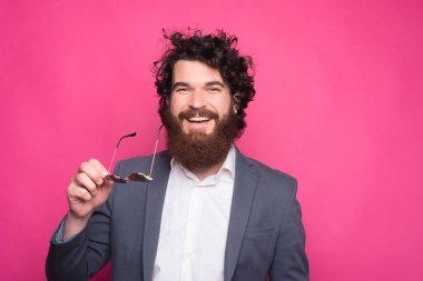 Takım elbiseli, elinde güneş gözlüğü olan gülümseyen genç adamın portresi..