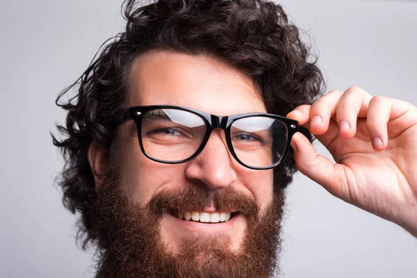 Close up retrato de homem hipster barbudo olhando para a câmera e tocando óculos — Fotografia de Stock