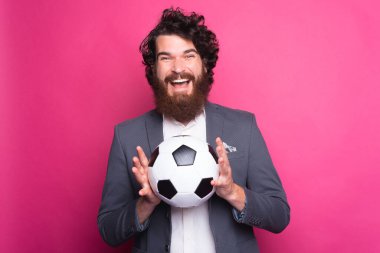 Sakallı, takım elbiseli ve elinde futbol topu tutan harika bir adam.