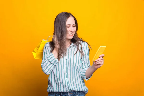 Retrato de menina feliz usando smartphone e segurando saco de compras — Fotografia de Stock