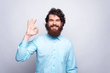 Mavi tişörtlü, neşeli ve sakallı bir adamın fotoğrafı.
