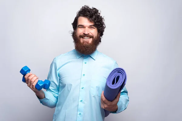 Retrato de hombre barbudo en mancuernas de celebración casual y esterilla de yoga, Hacer algunos ejercicios — Foto de Stock