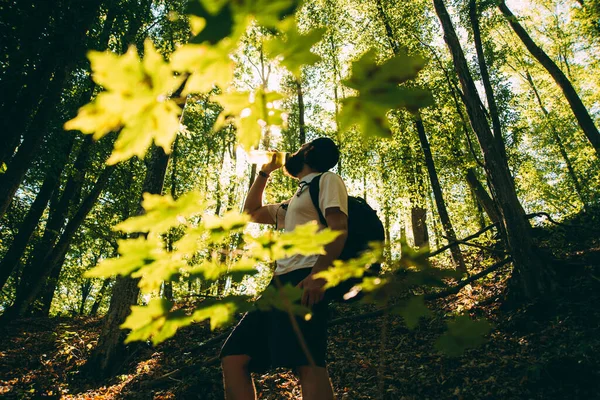 Photo of man hiking in forest and drinking water, resting — Stock Photo, Image